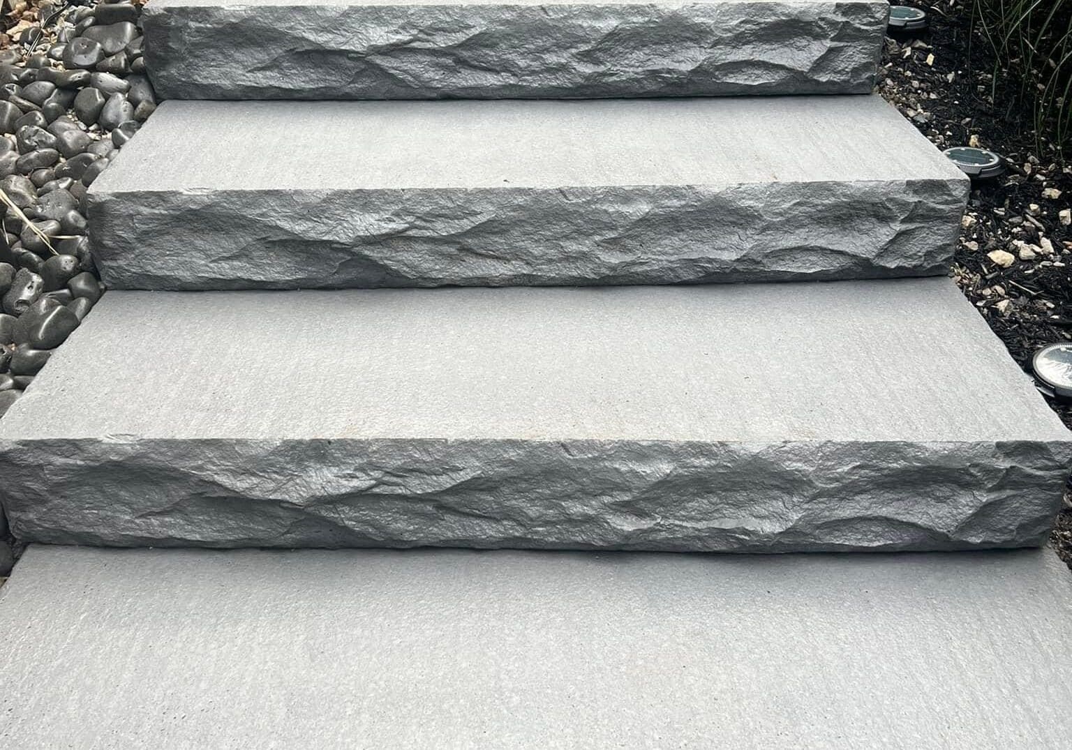 Gray stone outdoor steps installed on a landscaped walkway